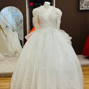 Bridal gown with V-neckline and long lace sleeves, embellished with pearls, silver stitching, and sparkling jewels